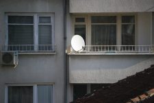 Mensen in Brussel hangen een satteliet antenne buiten en kijken satelliet tv